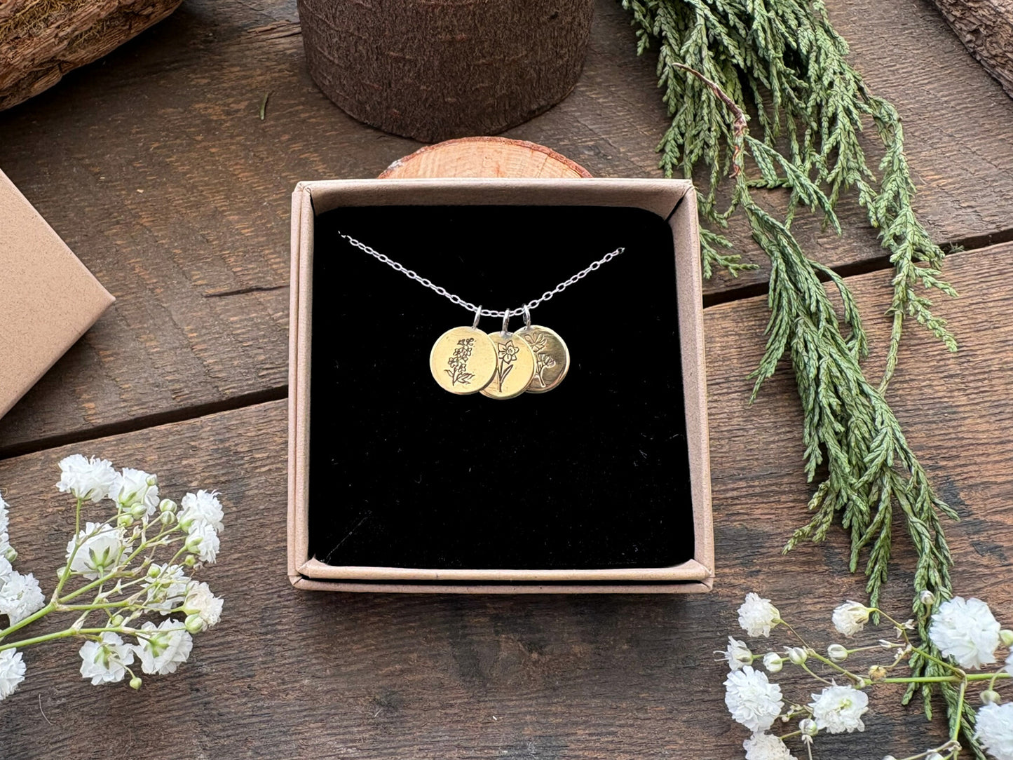 Brass birth flower bouquet necklace by curious magpie jewellery featuring charms on a necklace with engraved birth flowers on each charm.