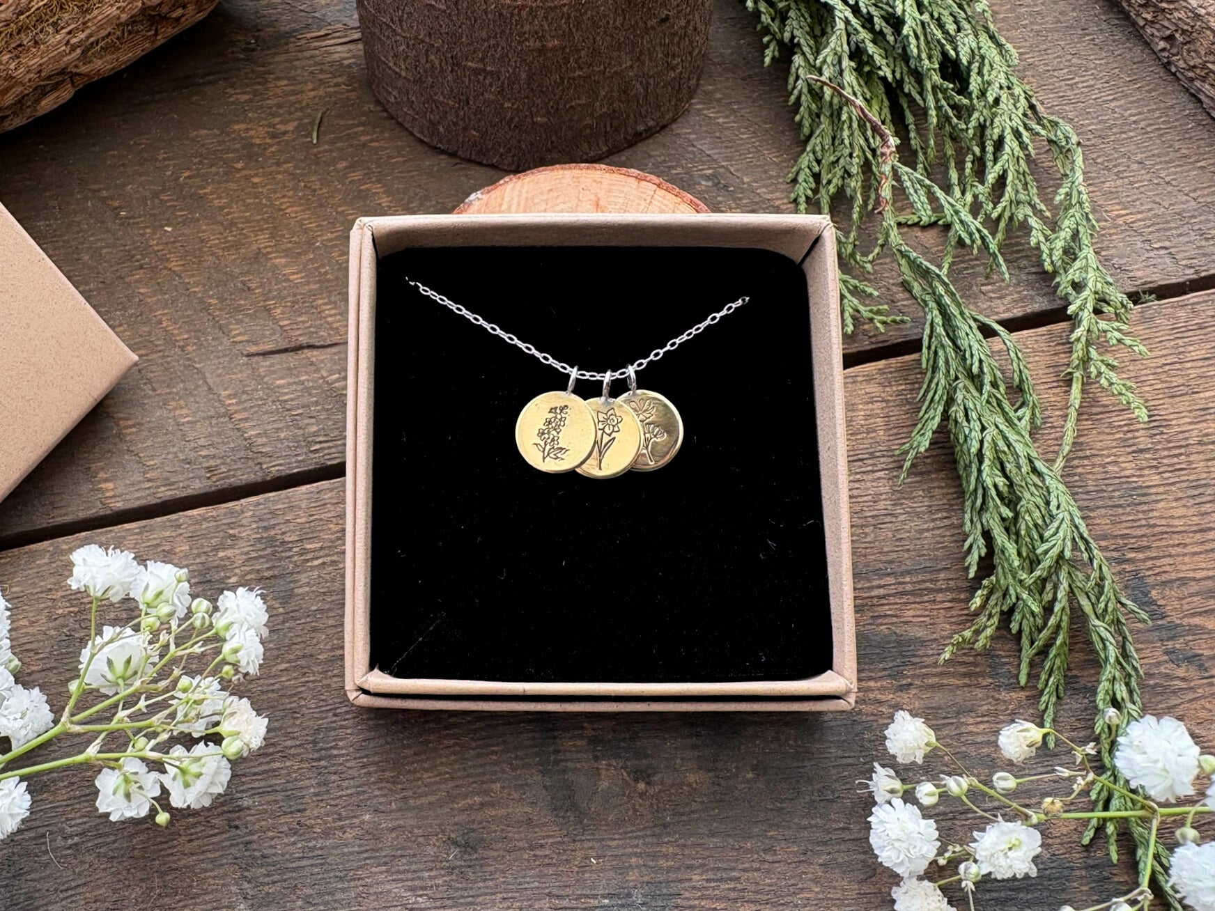 Brass birth flower bouquet necklace by curious magpie jewellery featuring charms on a necklace with engraved birth flowers on each charm.