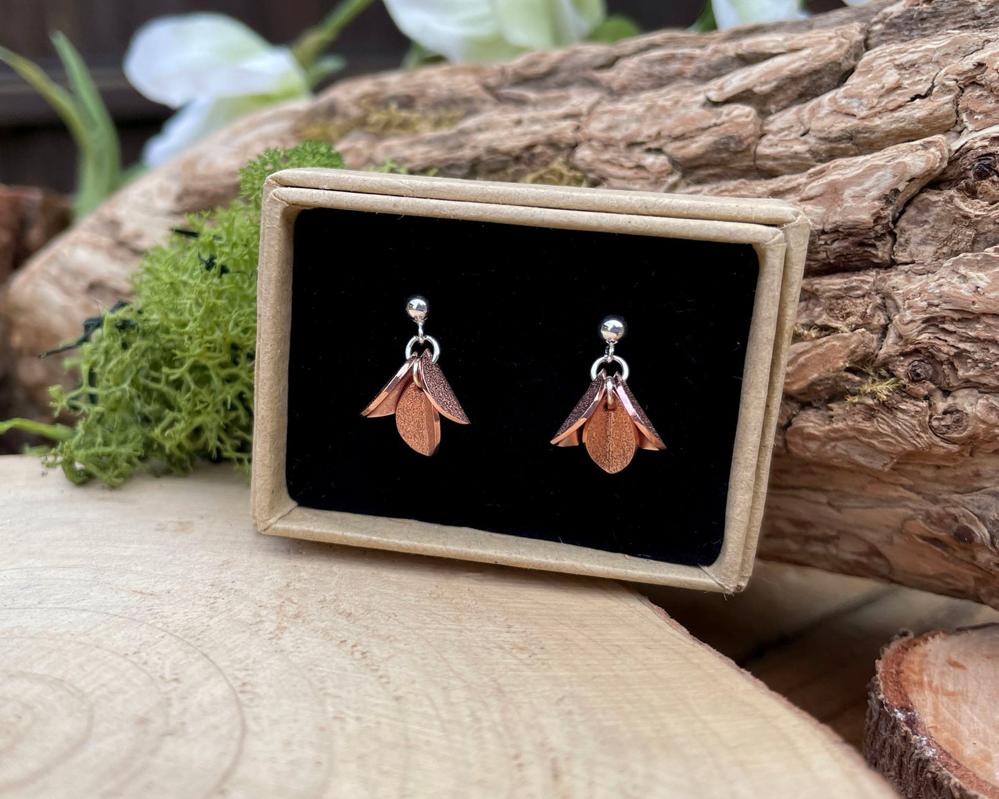 Pair of earrings on a black card with a wooden background