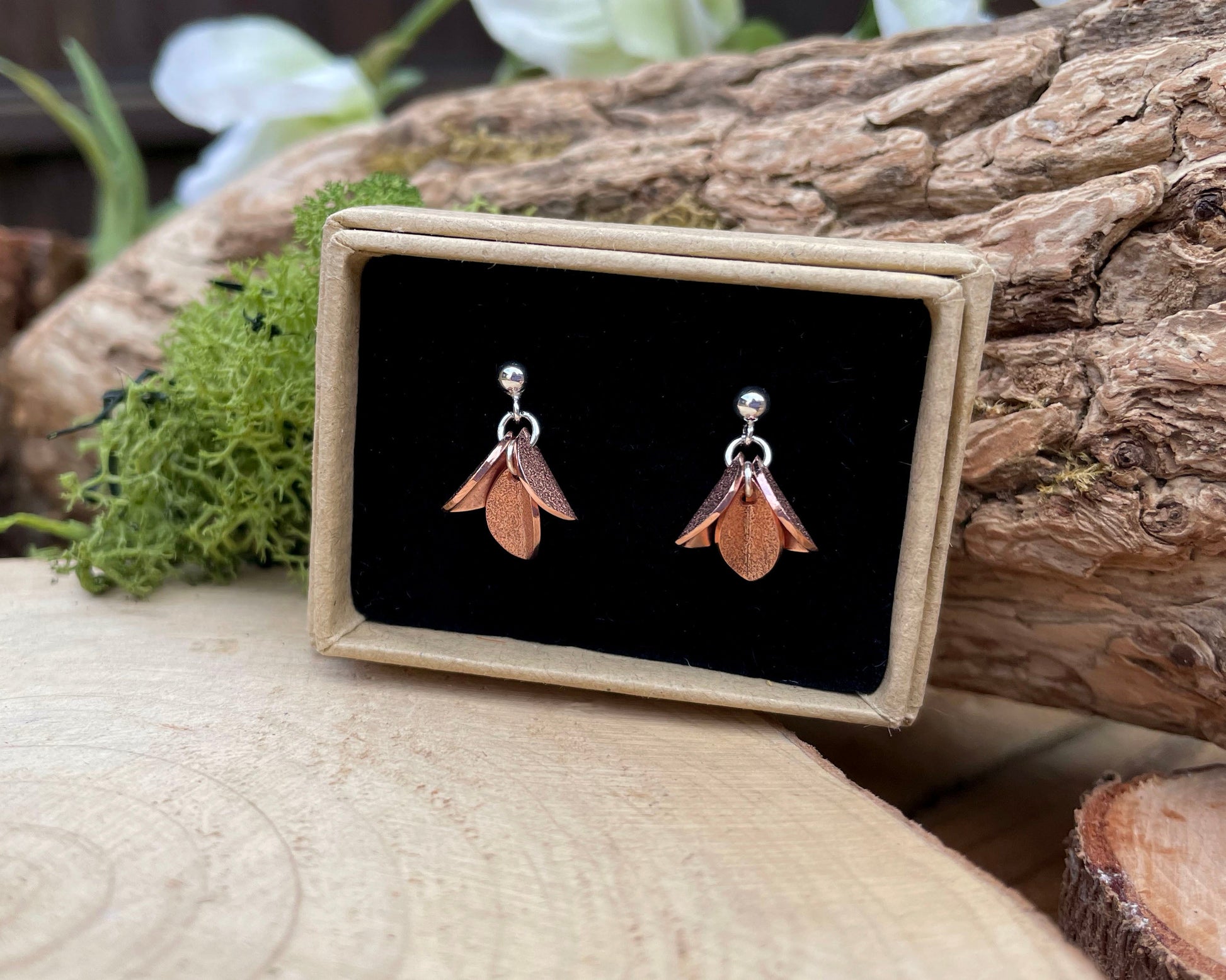 Pair of earrings on a black card with a wooden background