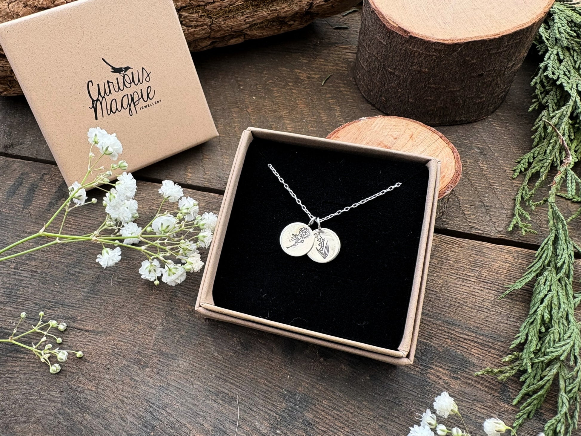 Sterling silver birth flower bouquet necklace by curious magpie jewellery featuring charms on a necklace with engraved birth flowers on each charm.