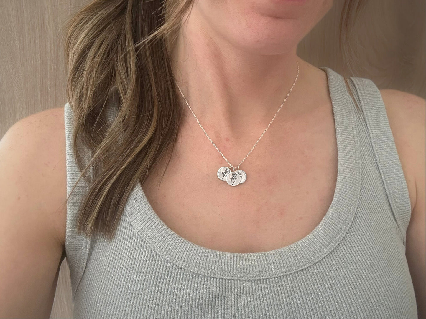 Sterling silver birth flower bouquet necklace by curious magpie jewellery featuring charms on a necklace with engraved birth flowers on each charm.