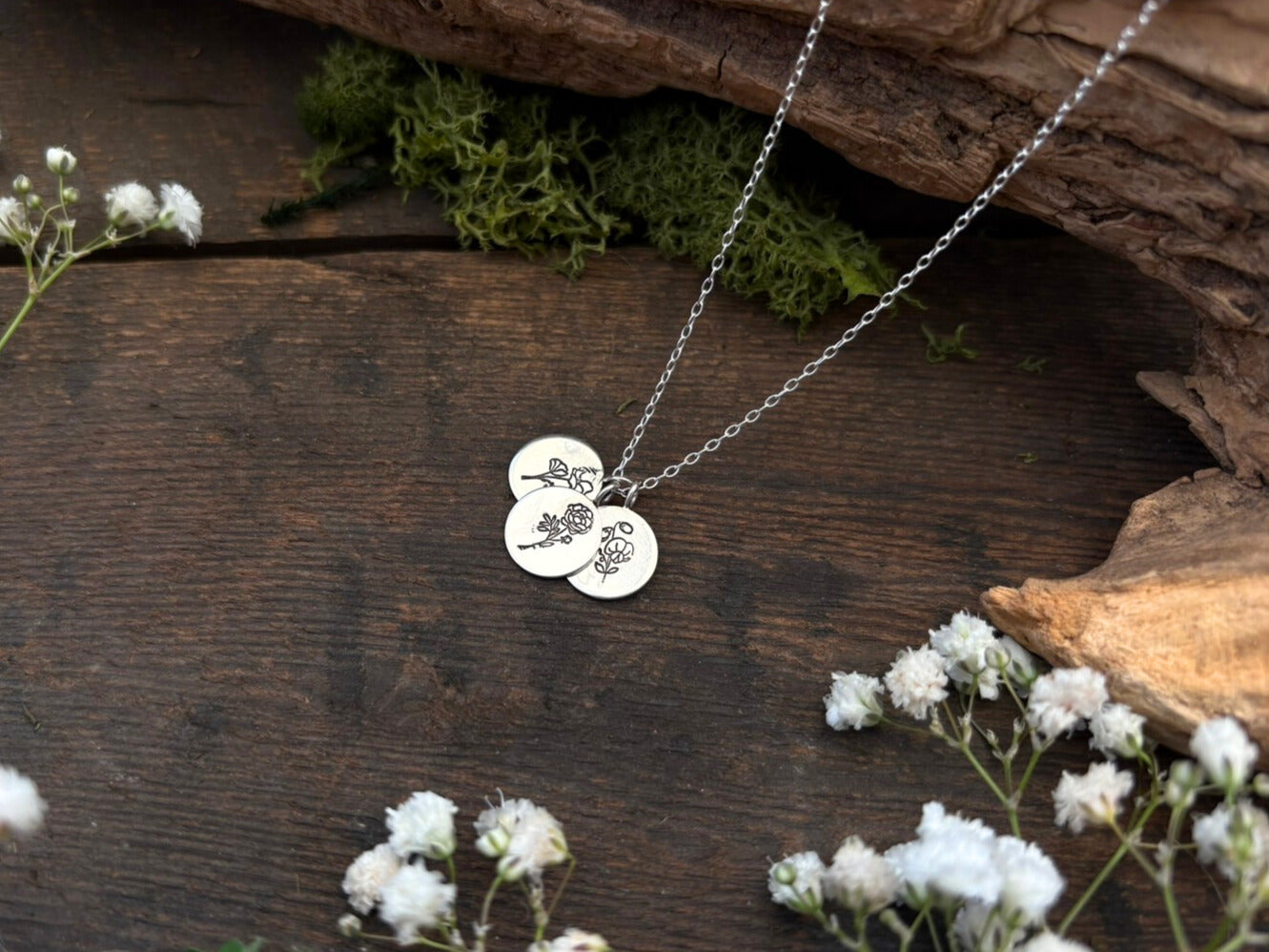 Sterling silver birth flower bouquet necklace by curious magpie jewellery featuring charms on a necklace with engraved birth flowers on each charm.