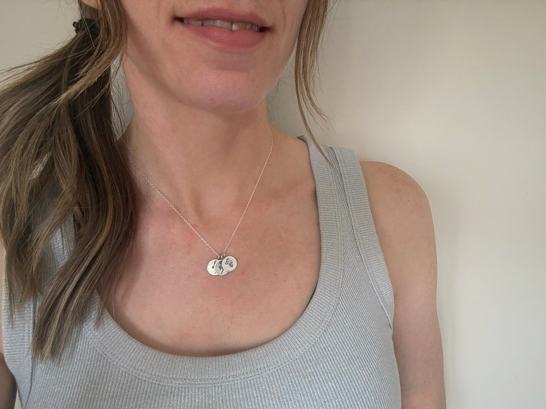 Sterling silver birth flower bouquet necklace by curious magpie jewellery featuring charms on a necklace with engraved birth flowers on each charm.