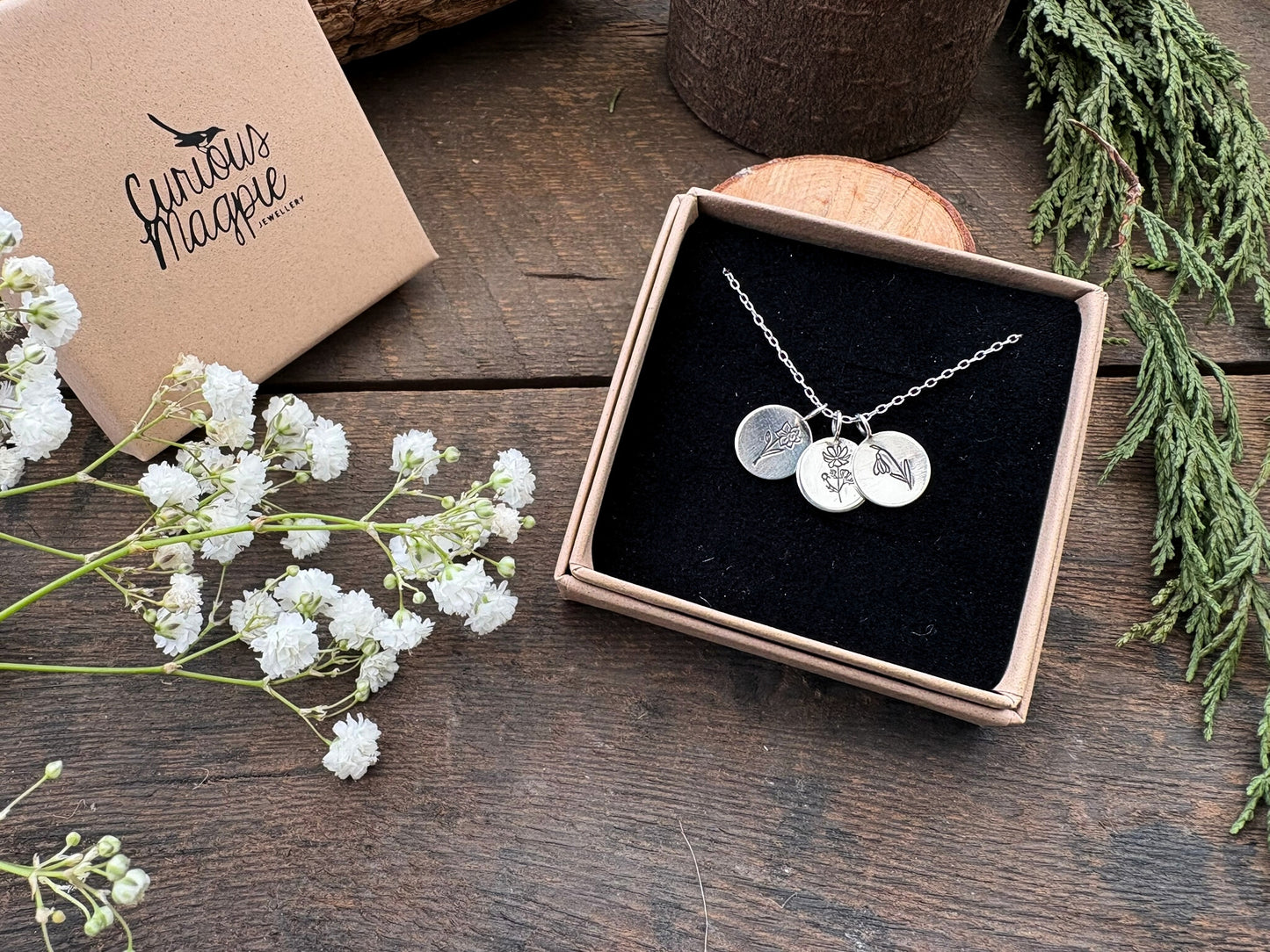 Sterling silver birth flower bouquet necklace by curious magpie jewellery featuring charms on a necklace with engraved birth flowers on each charm.