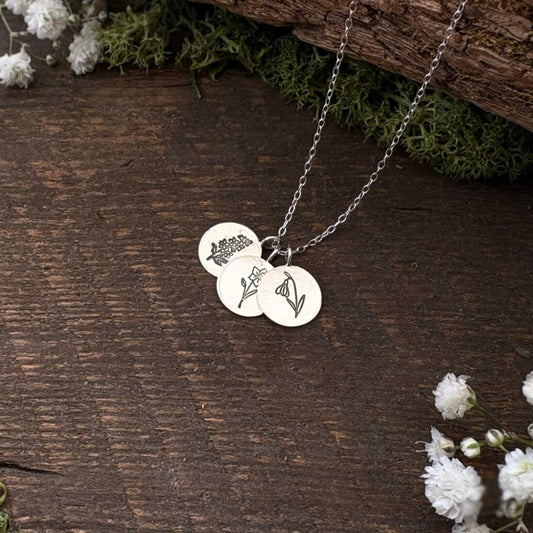 Sterling silver birth flower bouquet necklace by curious magpie jewellery featuring charms on a necklace with engraved birth flowers on each charm.